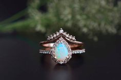 a white opal and diamond ring sitting on top of a table