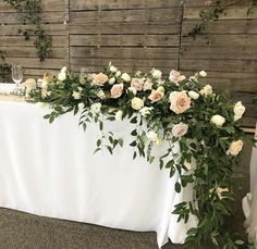 the table is covered with white flowers and greenery for an elegant wedding or reception