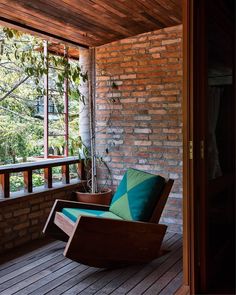 a rocking chair sitting on top of a wooden deck next to a window filled with plants