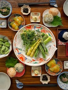 a table topped with plates and bowls filled with different types of food next to chopsticks