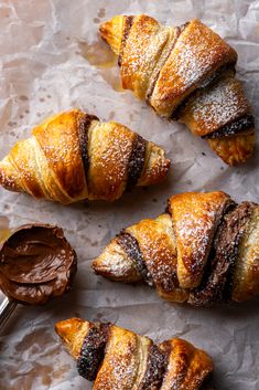 croissants with powdered sugar and chocolate spread on them next to a spoon