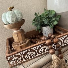 a wooden tray with two pumpkins on it and some tassels hanging from the handles