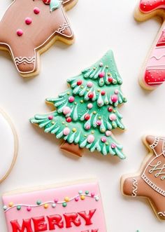 christmas cookies decorated with icing and decorations on a white surface, including gingerbreads