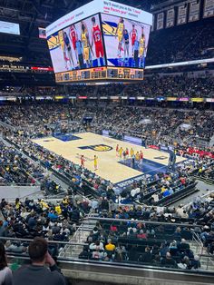 an indoor basketball court with people watching it from the bleachers in front of them