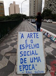 a sign that is on the sidewalk in front of some buildings and people walking by