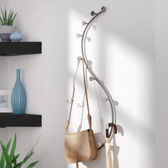 a white wall with some black shelves and a purse hanging from it's side