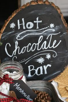 a hot chocolate bar with cookies and marshmallows is displayed in front of a chalkboard sign