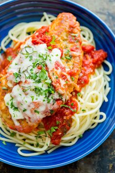 a blue plate topped with pasta and chicken parmesan covered in marinara sauce