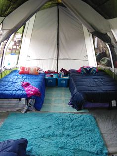 two beds in a tent with blue rugs