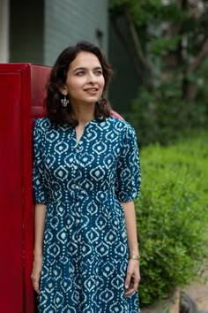 The cotton dress is handblock printed in a beautiful indigo color. It features a collar neck and elbow sleeves for a classic look. The dress is highlighted with shell buttons, adding a unique touch. The back has an elastic waist for a comfortable and fitted silhouette. DISCLAIMER: Natural-dyed colours might... Dress Neck Patterns Indian Kurti Cotton, Indigo Churidar Design, Churidar With Collar Neck, Color Neck Kurti Designs Latest, Dress Indian Style Simple Cotton Neck Design, Collar Neck Dress Designs, Collar Neck Kurtis, Collar Suit Designs