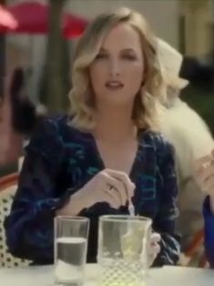 two women sitting at a table with drinks and food in front of them, talking