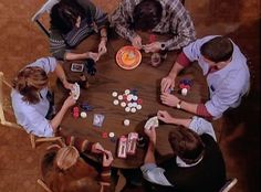 four people sitting around a table playing cards