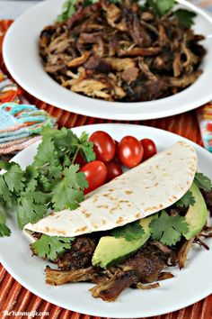 two white plates topped with tacos and veggies on top of a table