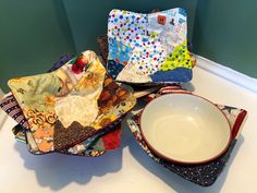 several pieces of fabric sit on top of a counter next to a bowl and plate