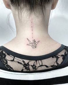 a woman's neck with a small origami tattoo on it