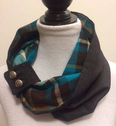 a white mannequin wearing a black and blue plaid scarf with buttons on it