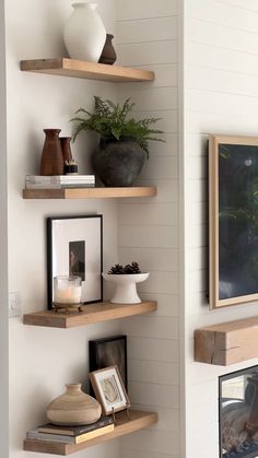 three wooden shelves with vases, pictures and other items on them in a living room