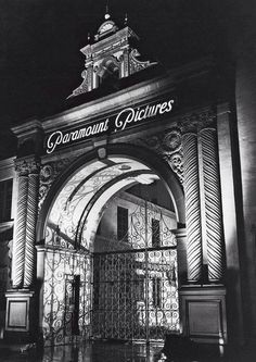 black and white photograph of an entrance to a building at night with the words paramount pictures on it