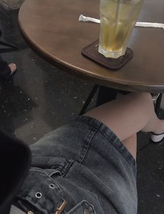 a person's legs resting on a table with a beverage in a glass next to them