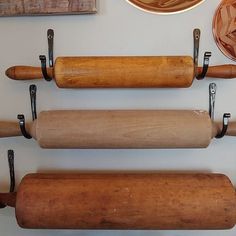 three rolling dough rollers are hanging on the wall next to a plate and other kitchen items