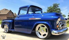 an old blue truck parked in front of a house