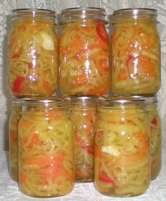 several jars filled with different types of food on a white tableclothed surface, each containing onions and carrots