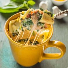 a yellow cup filled with pasta and spinach