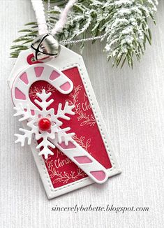 a red and white christmas ornament with snowflakes on it, hanging from a tree