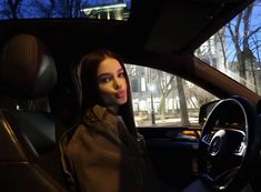 a woman sitting in the driver's seat of a car with her head turned to the side