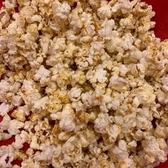 a red bowl filled with popcorn on top of a table