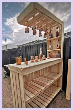 an outdoor bar made out of pallet wood with hanging lights and bottles on it