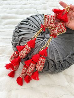 a hand holding onto a pillow with red tassels