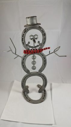 a snowman made out of metal with red beads and a top hat on it