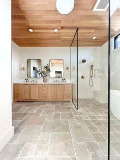 a large bathroom with two sinks, mirrors and a shower stall in the middle of the room