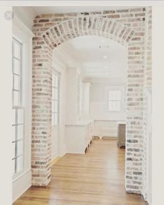 an empty room with white brick walls and wood flooring is seen in this image