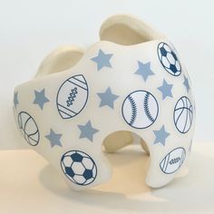 a toothbrush holder with sports balls and stars on the front, sitting on a white surface