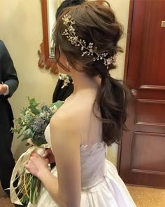 a woman in a wedding dress is looking at her bouquet while another man looks on