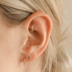 a close up of a woman's ear with two small gold hoops on it