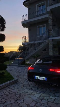 a black car parked in front of a building with stairs leading up to the top