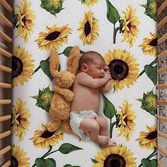 a baby sleeping in a crib next to sunflowers