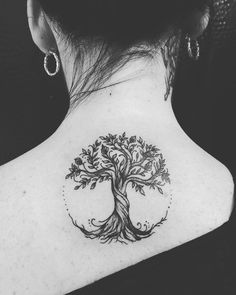 a woman's back neck with a tree tattoo on the upper part of her body