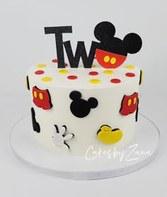 a white cake with mickey mouse decorations on it's top and the number two