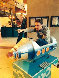 a man sitting on top of a toy rocket ship