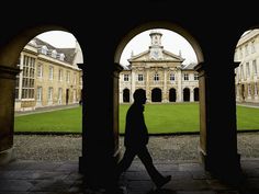 the silhouette of a man walking through an archway in front of a building with two arches