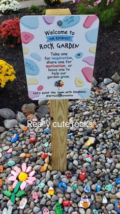 a rock garden sign surrounded by flowers and rocks