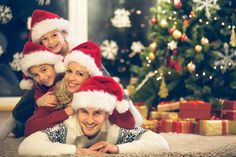 a family wearing santa hats laying on the floor in front of a christmas tree with presents