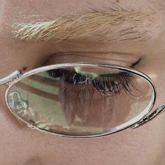 a close up of a person's eye wearing glasses with long hair and fake eyelashes