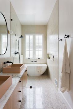 a large bathroom with two sinks and a bathtub in the middle, along with a mirror on the wall