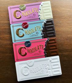 four chocolate bars are lined up on top of each other in different colors and shapes