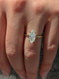 a woman's hand with a diamond ring on top of her finger, showing the center stone